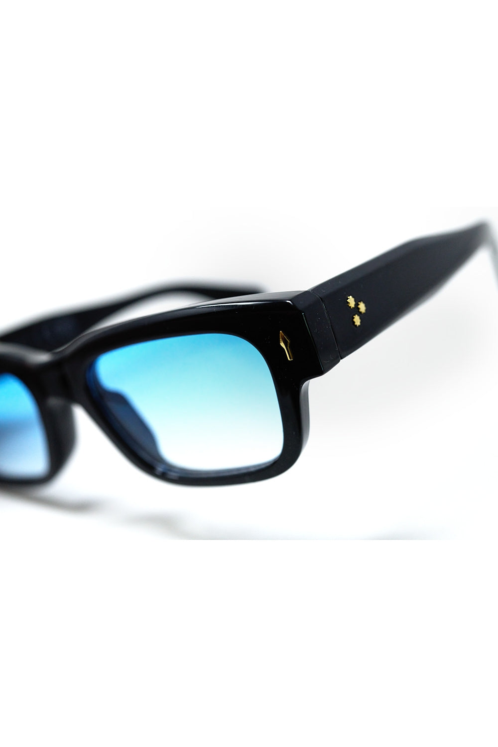 Gafas de sol negras con montura ovalada con detalle dorado y cristal azul Q2