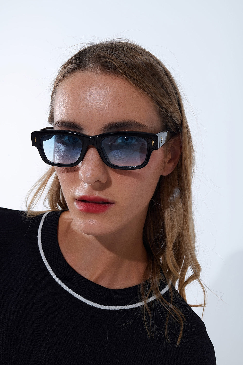 Gafas de sol negras con montura ovalada con detalle dorado y cristal azul Q2